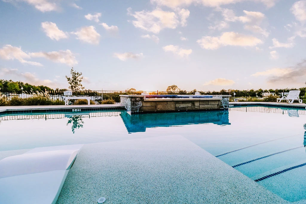 Pool, spa deck, and loungers tucked into landscaping — cool water, warm evenings, and resort comfort steps from your site.